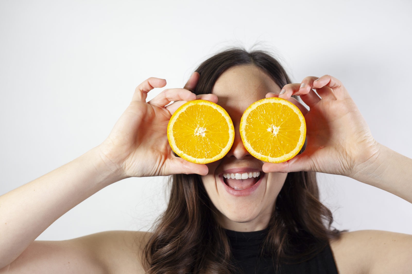 woman holding oranges in place of eyes