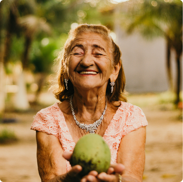 Elderly woman holding a fruit smiling