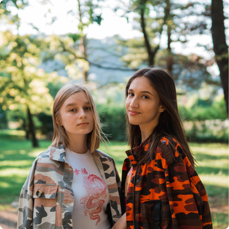 Two young women looking at the camera in a park