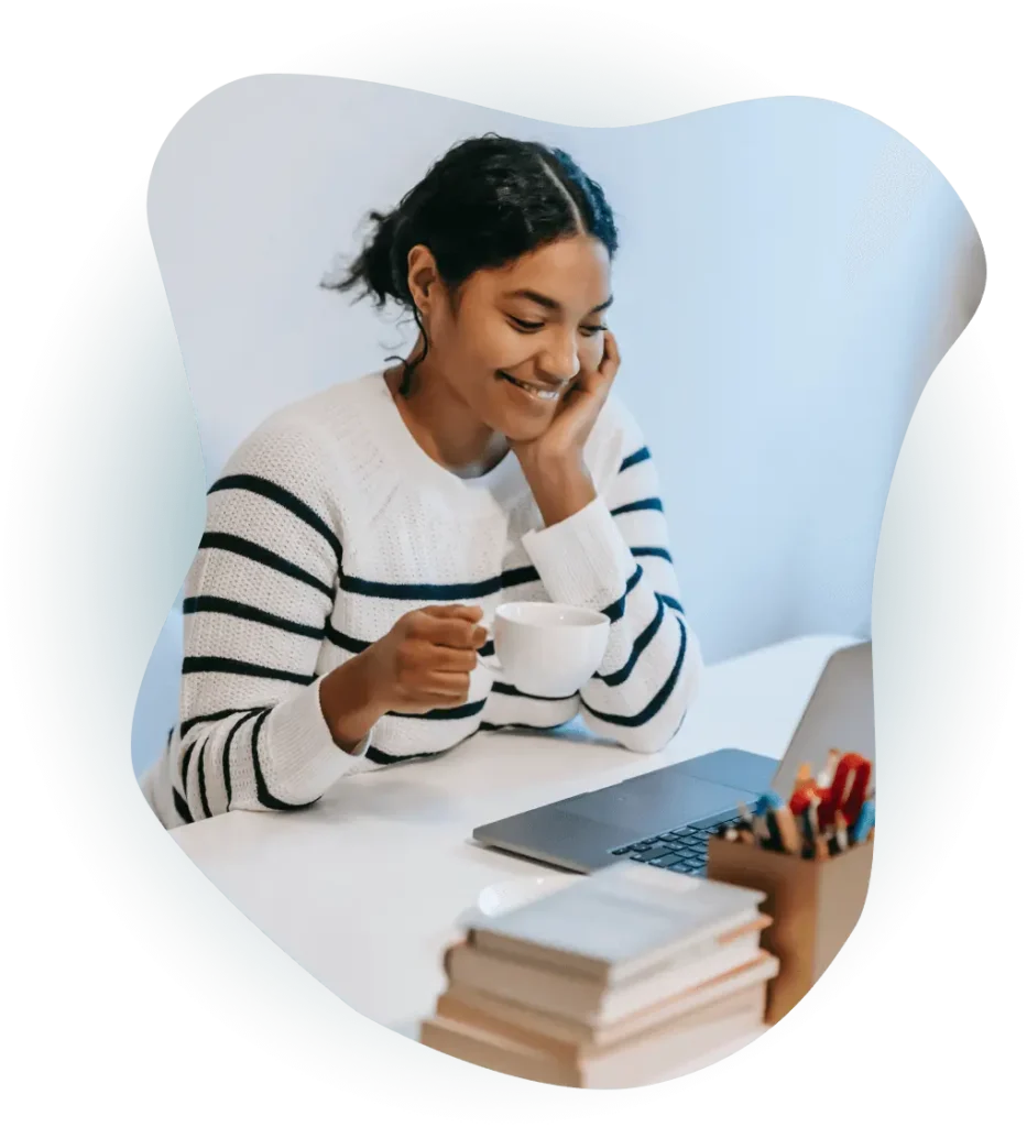 Woman drinking coffee looking at laptop