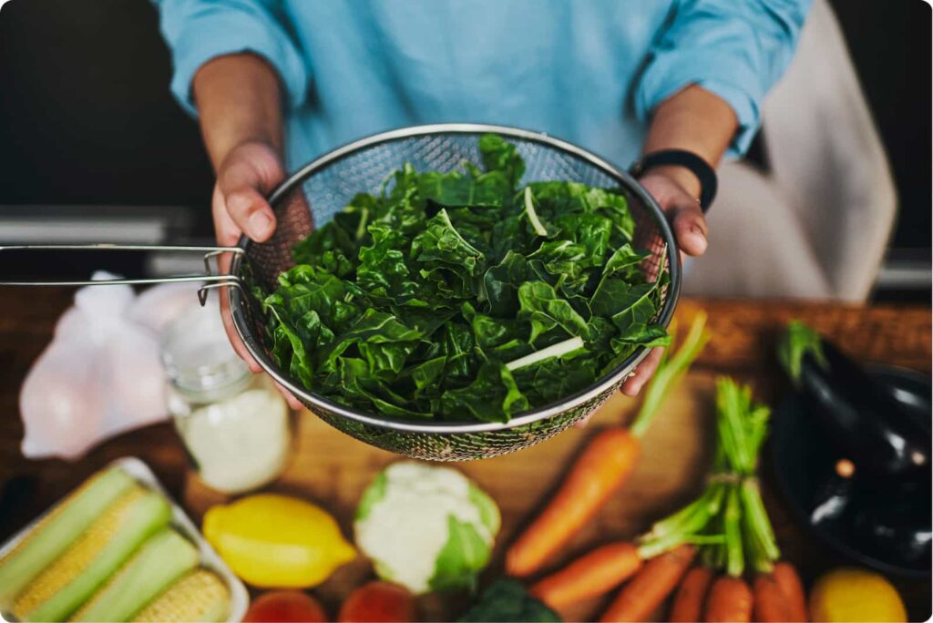 Collard greens in a strainer held by two hands