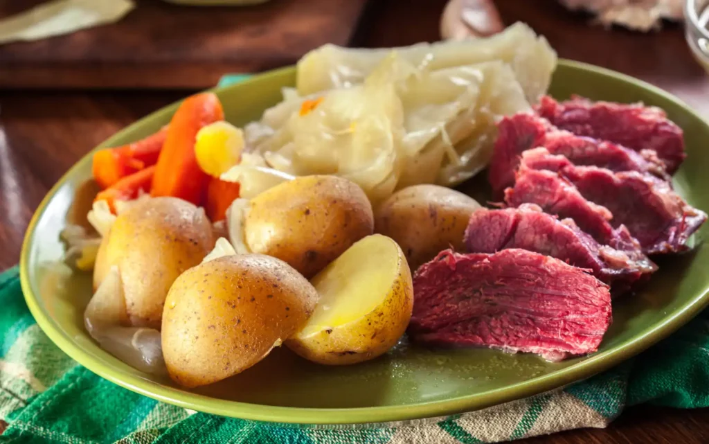 Corned beef, potatoes, and carrots on a green plate.