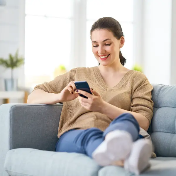 Woman on a sofa looks at the phone smiling
