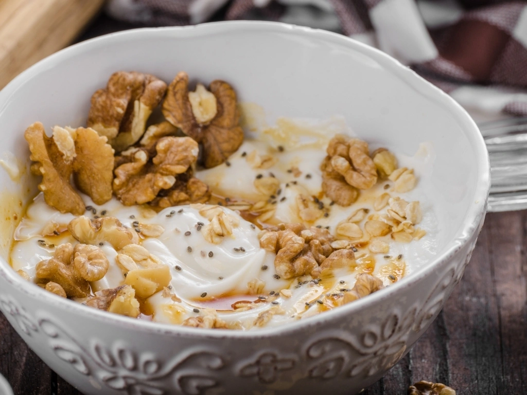 Bowl of yogurt with walnuts, chia seeds, and a drizzle of honey