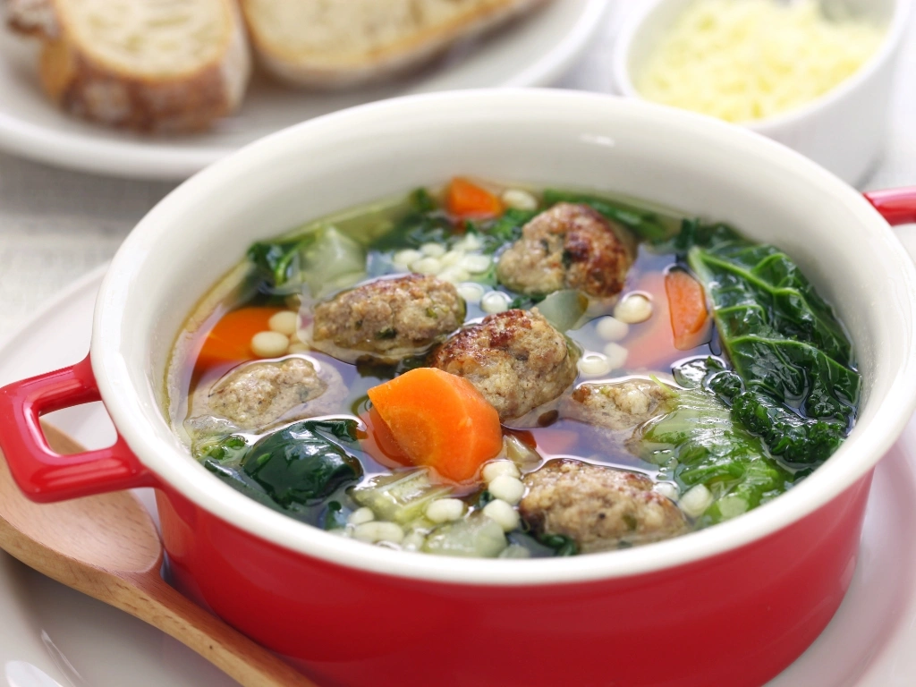 Italian wedding soup in a red ramekin