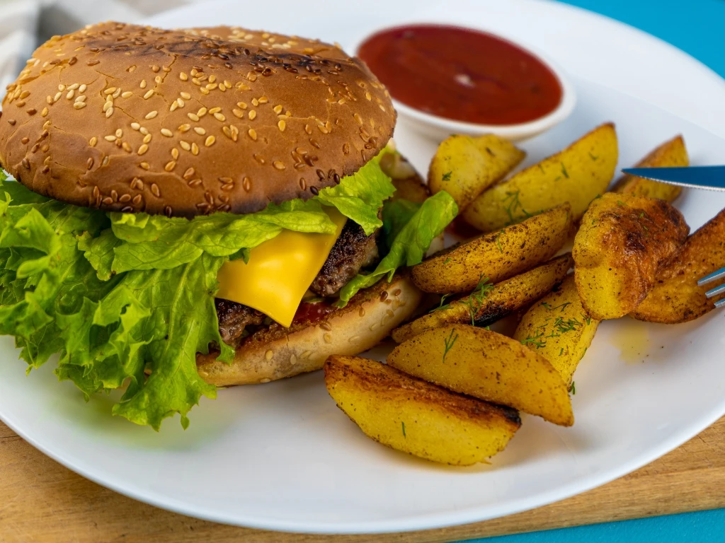 Homemade cheeseburger served with roasted potatoes and ketchup