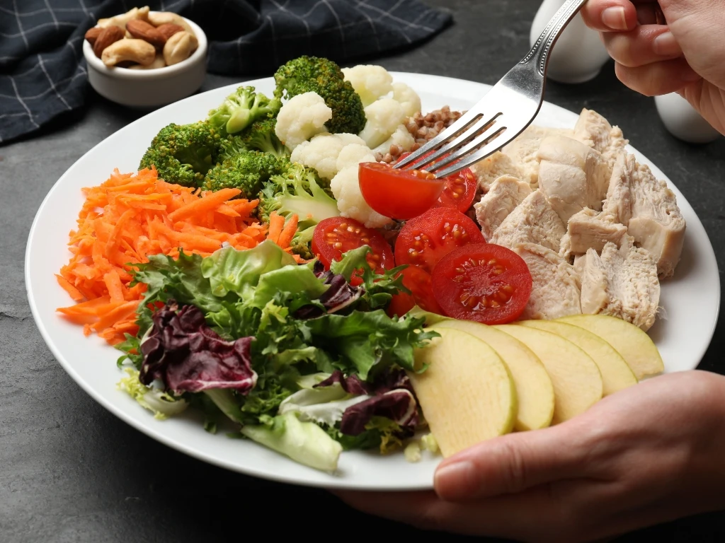 Person eating a plate full of healthy foods