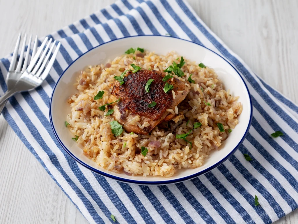Roasted ginger chicken thigh served over a bowl of seasoned brown rice and garnished with fresh parsley