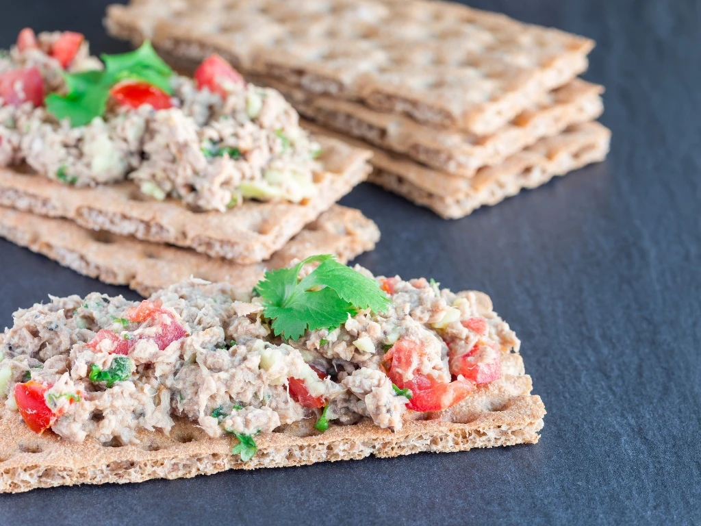 Whole-grain crackers topped with tuna salad and herbs