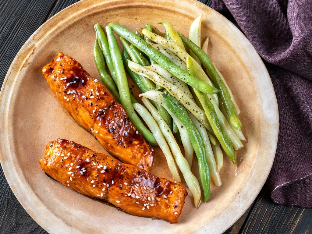 Plate of two teriyaki salmon slices and steamed green beans