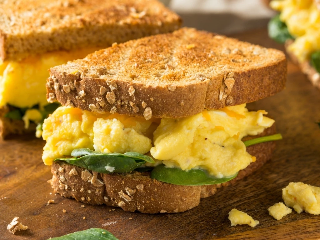 Egg and spinach sandwiches on a wooden board