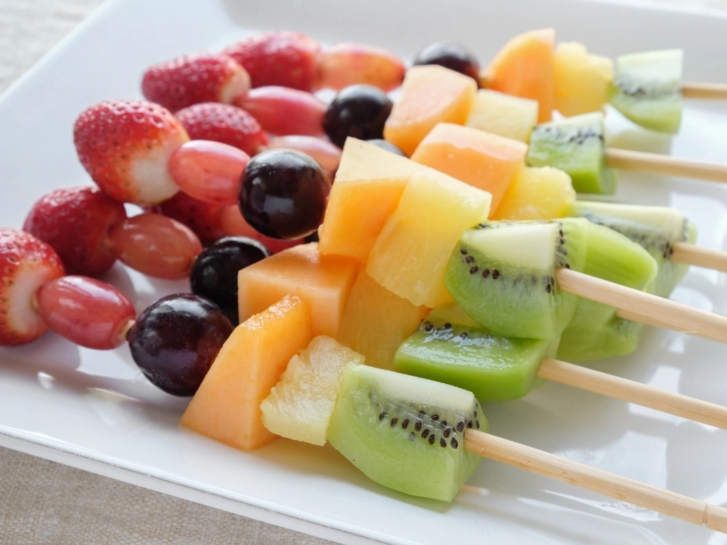Various fruits arranged into skewers on a white plate