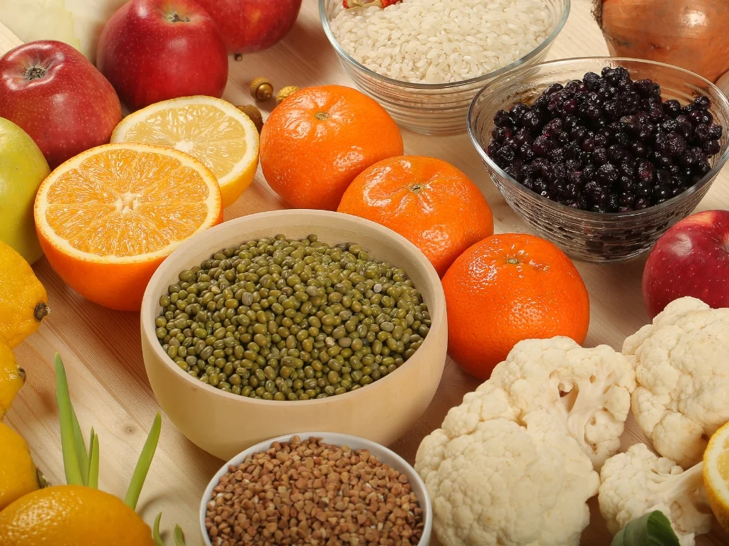 Various fruits, vegetables, and bowls full of different beans