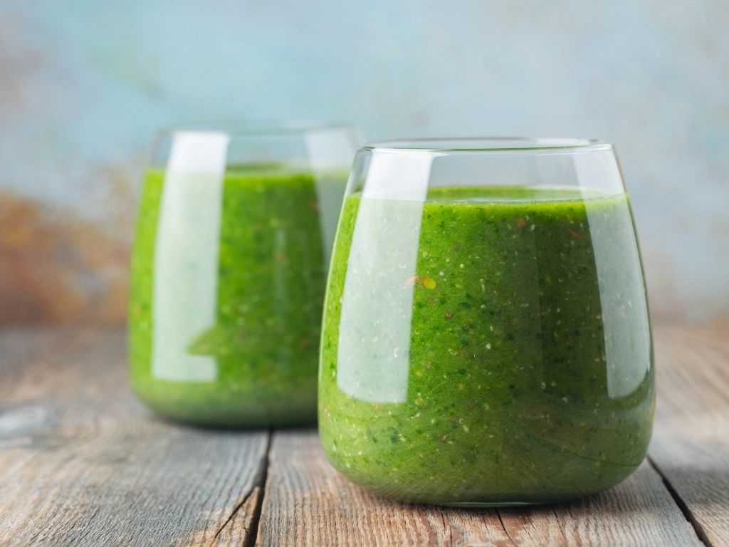 Two glasses of green smoothie on a wooden table