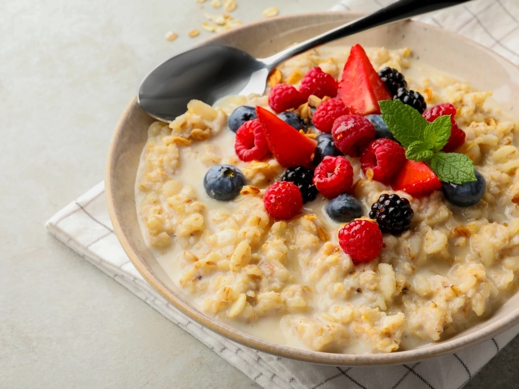 Bowl of oatmeal topped with assorted fresh berries and served with a spoon