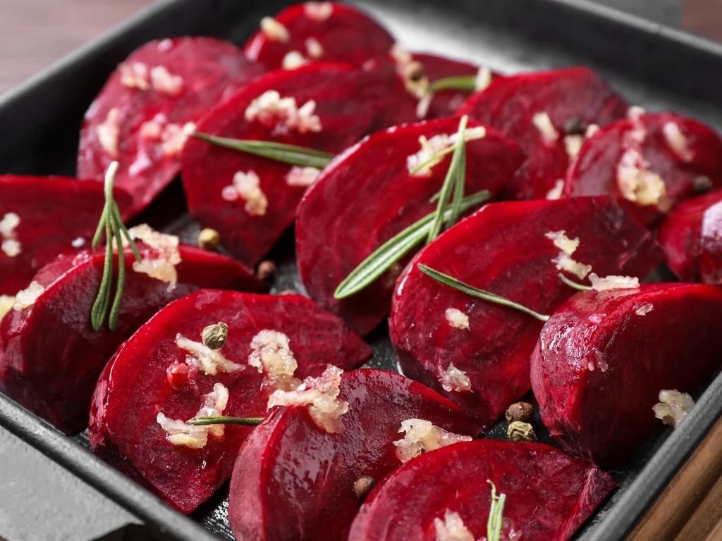 Slices of beets arranged in a square black dish, garnished with herbs