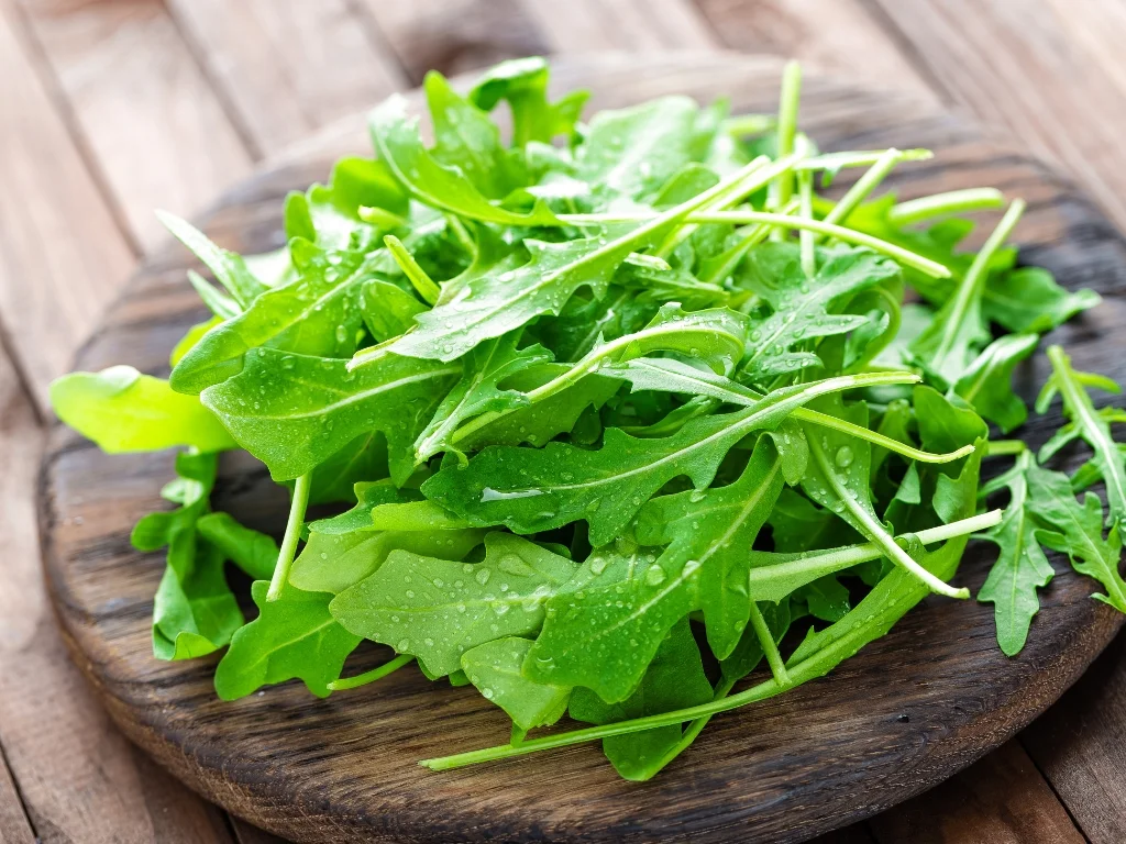 Fresh arugula leaves on a round wooden board