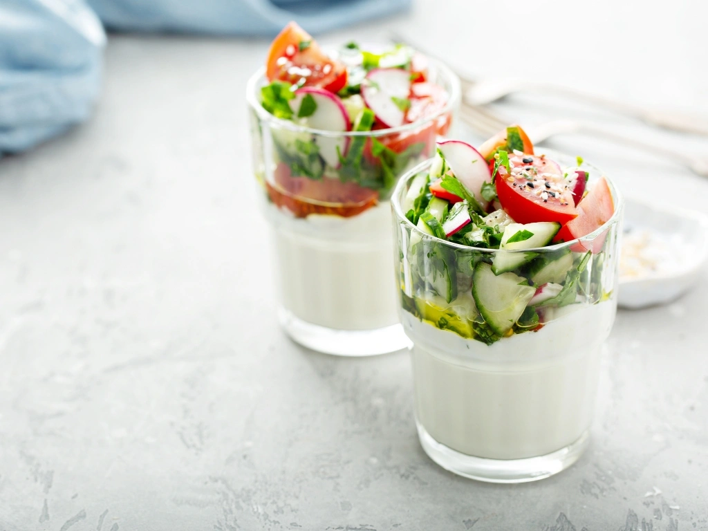 Two glasses of sliced garden vegetables, herbs, and tzatziki