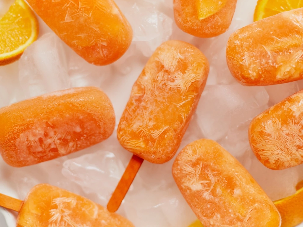 Homemade orange popsicles and orange slice on ice cubes