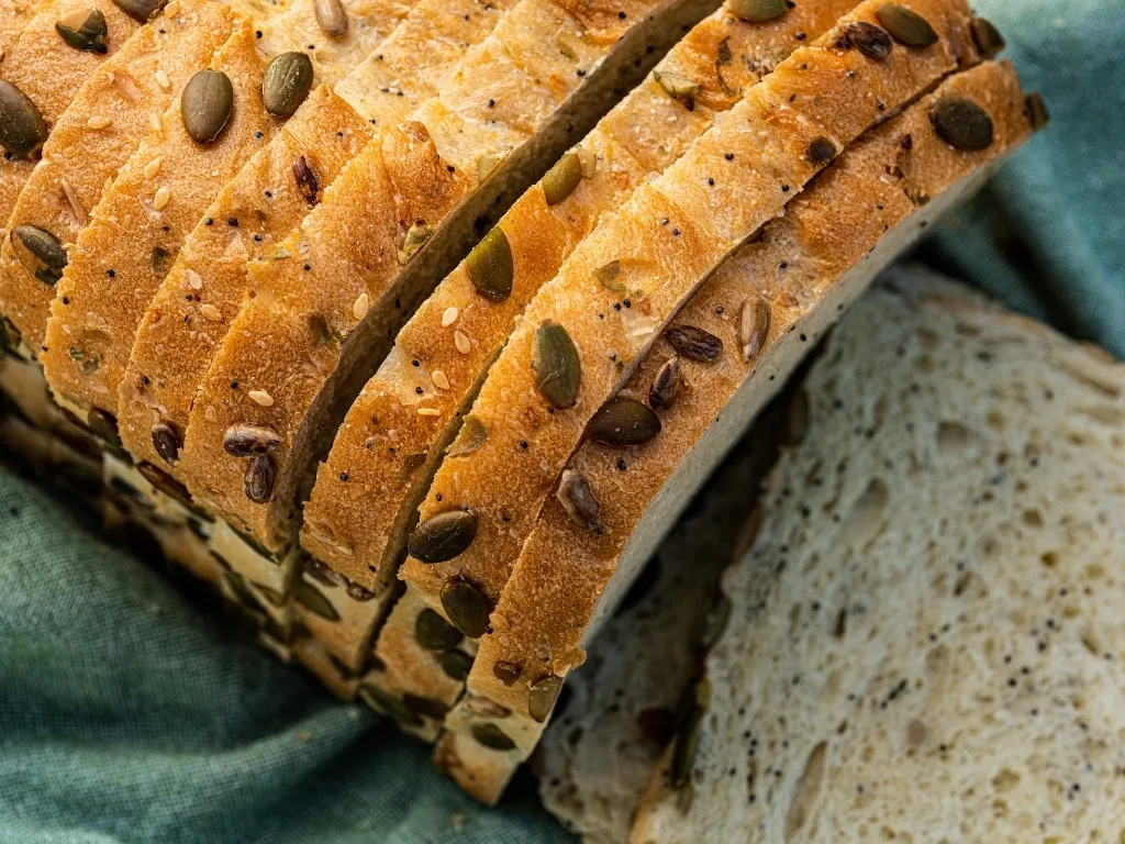 Sliced loaf of sprouted grain bread on a green tablecloth