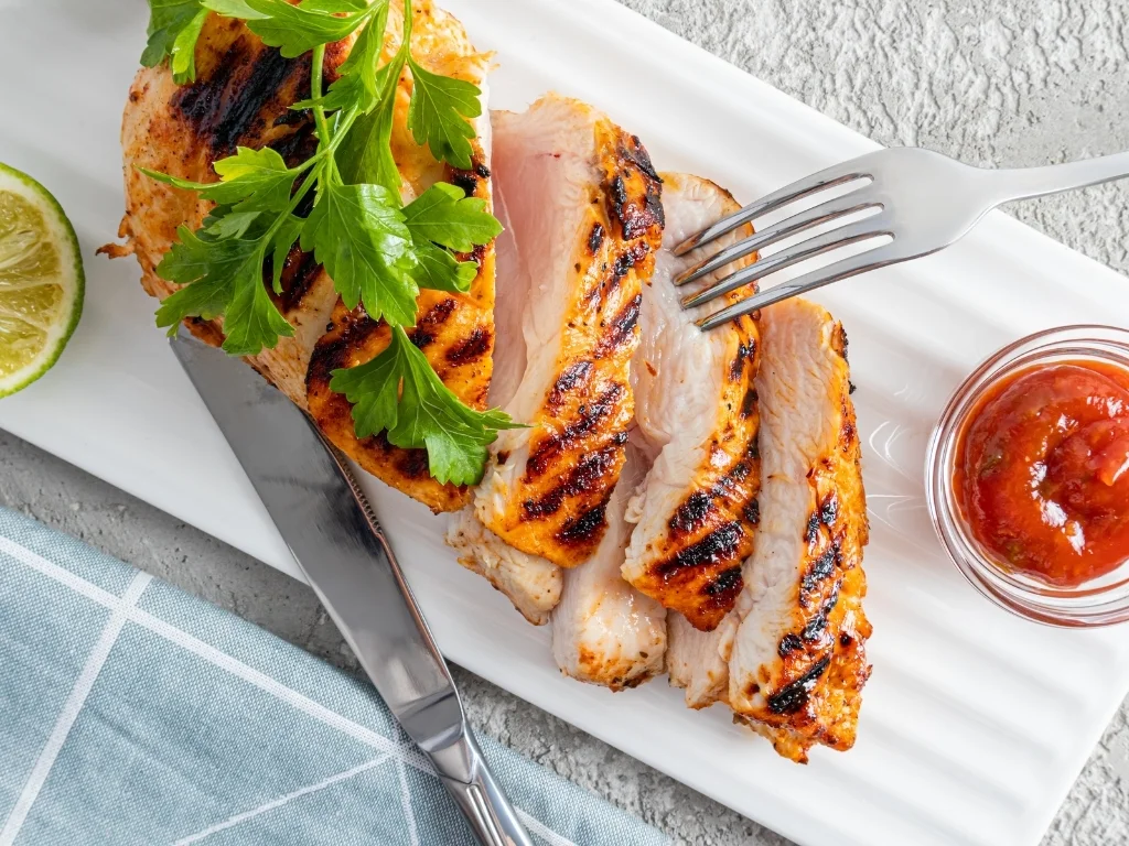 Slices of grilled chicken breast arranged on a rectangular plate