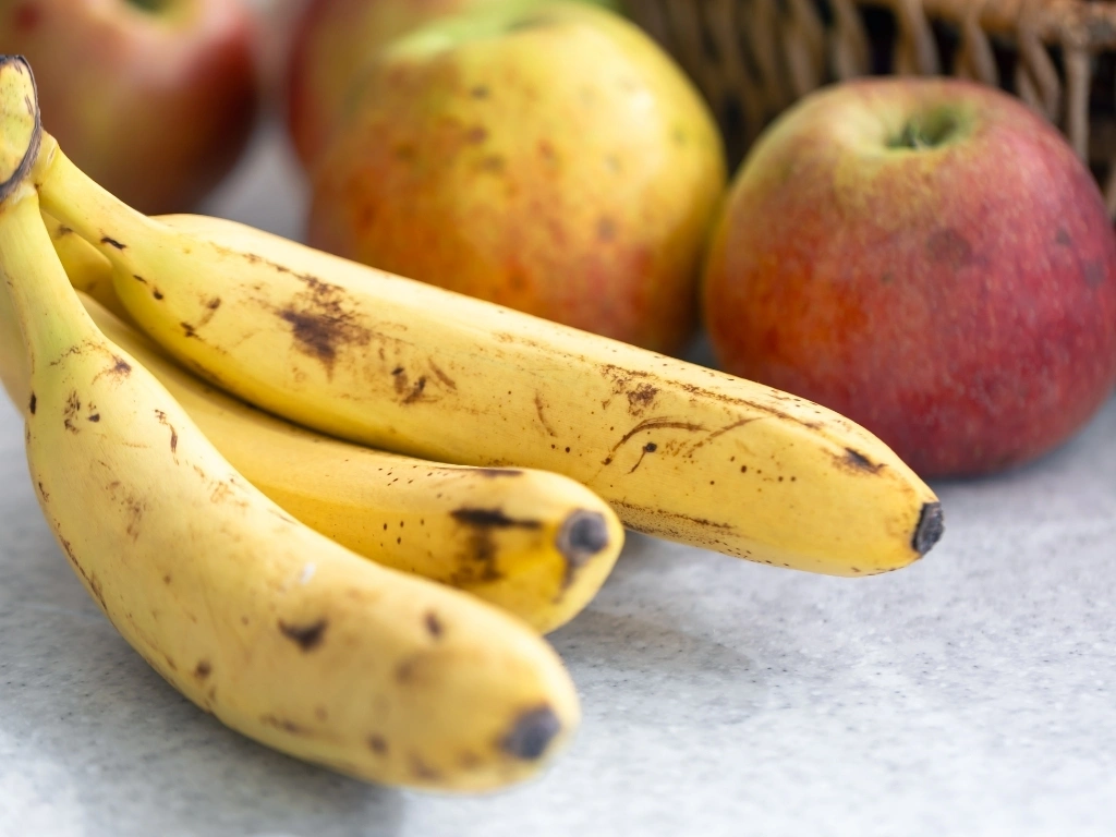 A bunch of ripe bananas next to apples