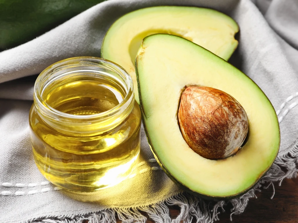 Jar of avocado oil next to fresh avocado slices