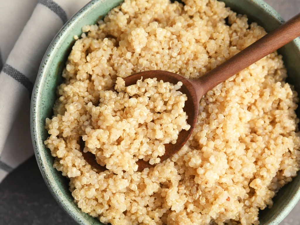 Wooden spoon in a bowl of cooked quinoa