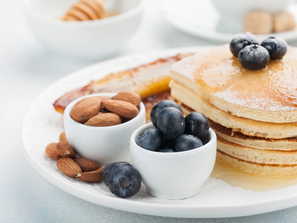 Stack of pancakes, drizzled with syrup and topped with fresh blueberries