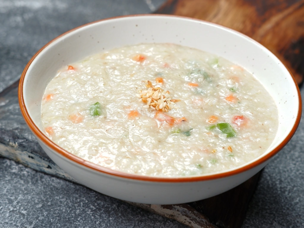 Bowl of vegetable congee garnished with sesame seeds