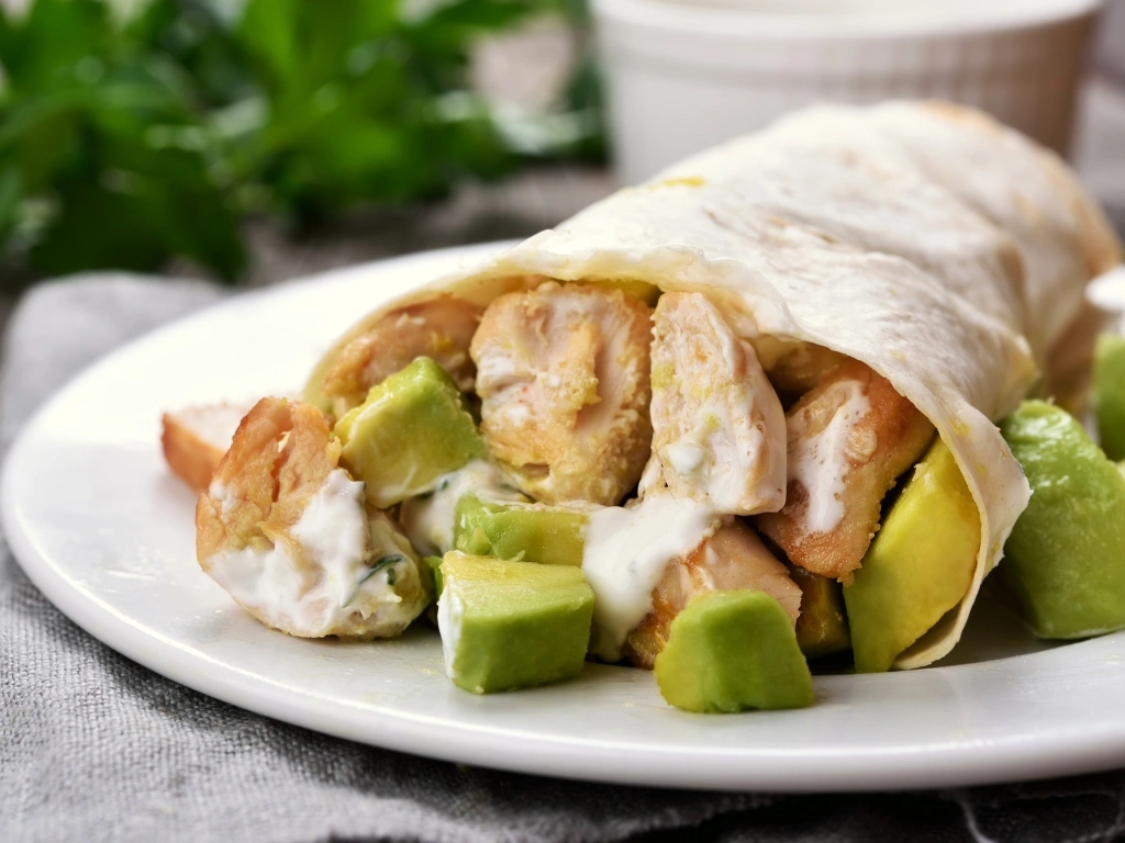 Chicken and avocado wrap on a white plate