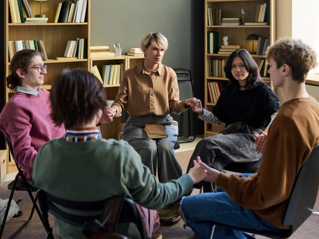 A group of young people sitting in a circle and holding hands