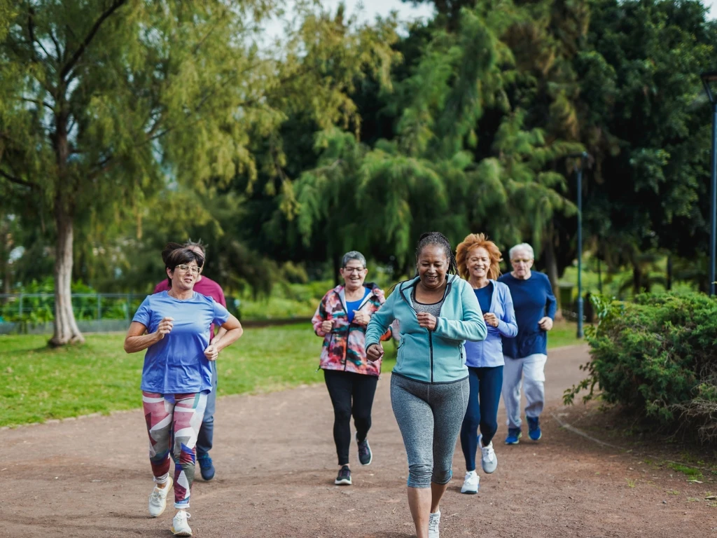 Individuals from varied age groups jogging together at a lush green park