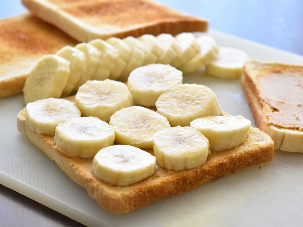Slices of bread, some toasted and others topped with sliced banana