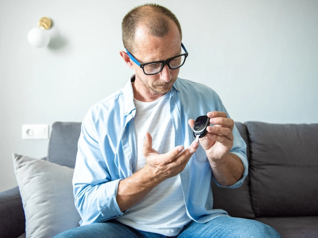 Man taking blood sample from his finger to monitor glucose levels