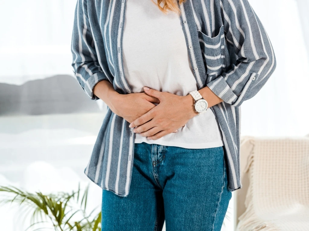 Woman standing up while holding her abdomen in pain