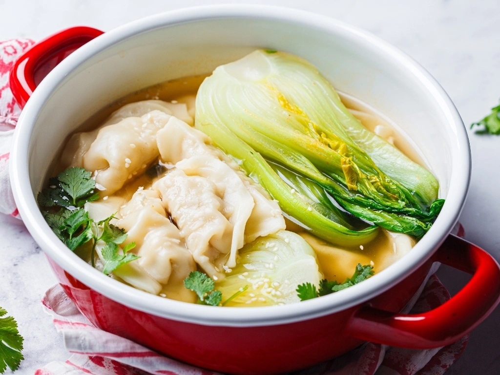 Chicken wonton and bokchoy soup in a red casserole