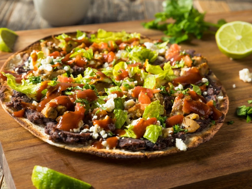 Black bean tostadas on a wooden board, surrounded by lime slices