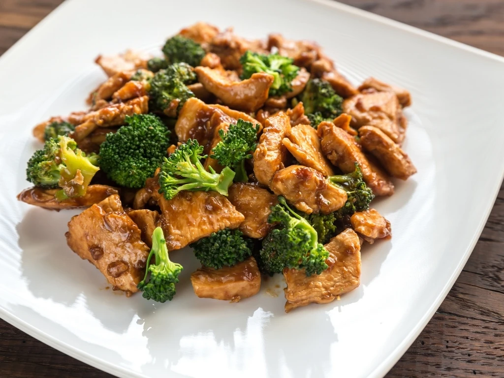 Stir-fry chicken with broccoli served on a white square plate