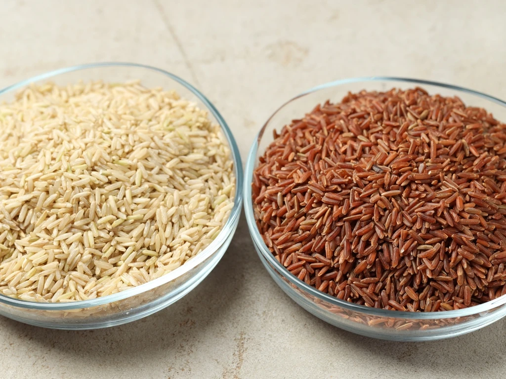 Uncooked white and red rice in separate clear bowls