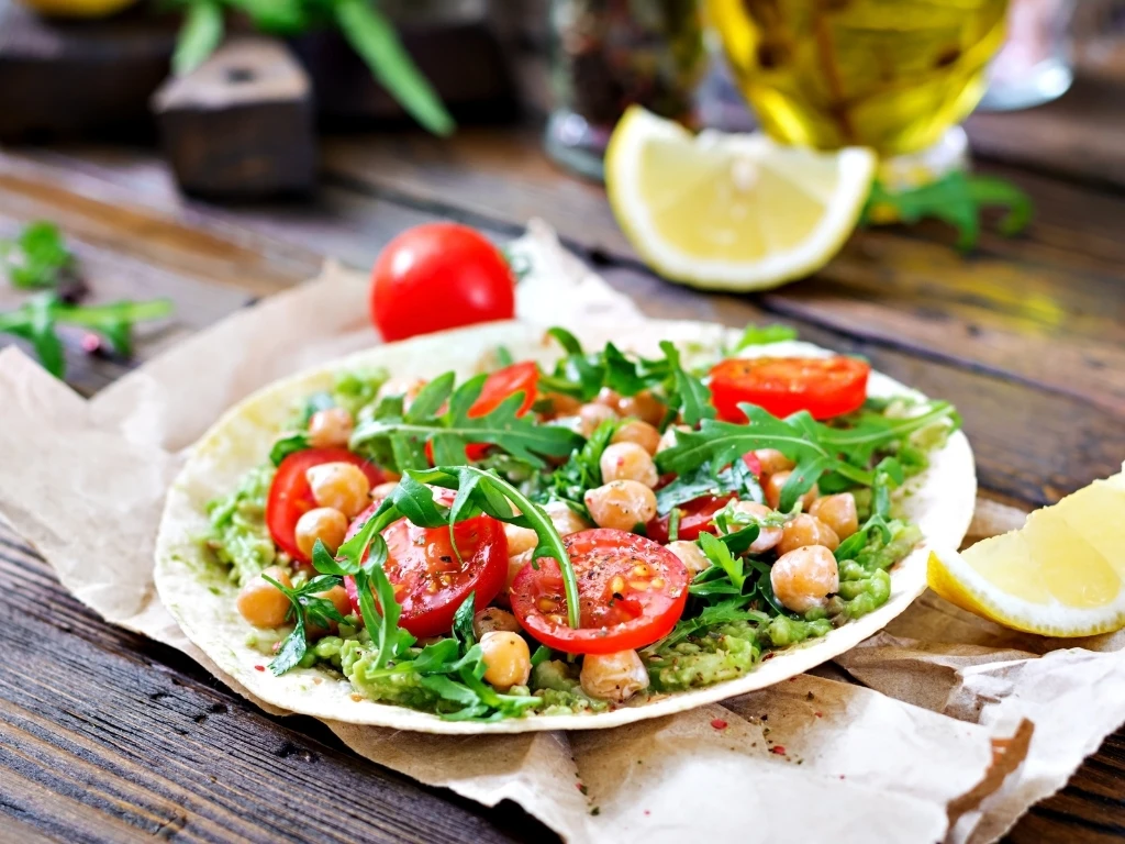 Whole-wheat pita topped with smashed avocado, cherry tomatoes, chickpeas, and arugula, served with lemon wedges