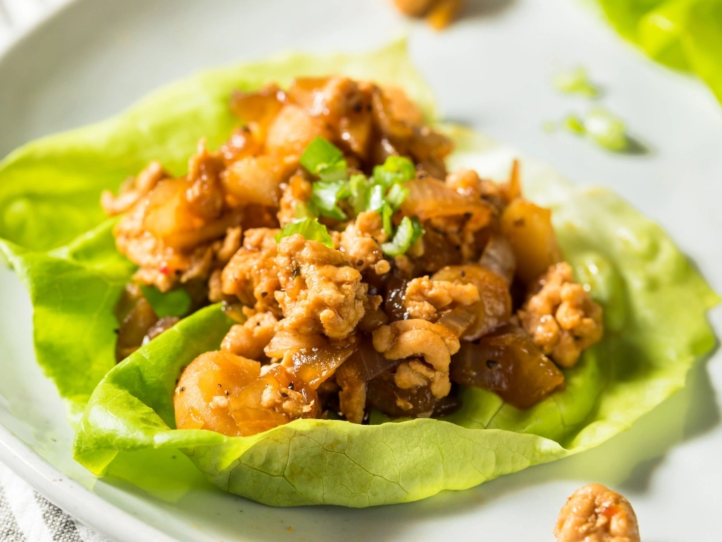 Ground turkey and herbs wrapped in a piece of lettuce and served on a white plate