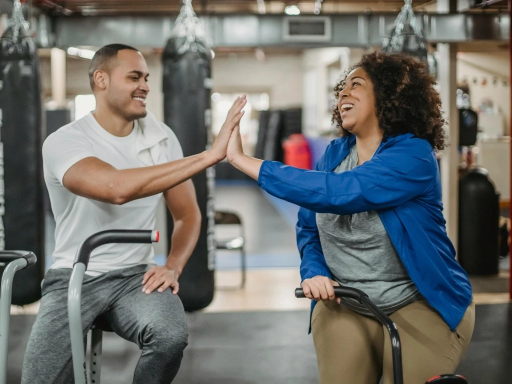 Man and woman high-fiving during a workout at the gym