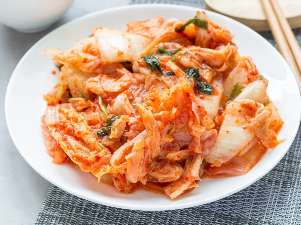 Kimchi served on a white plate with chopsticks