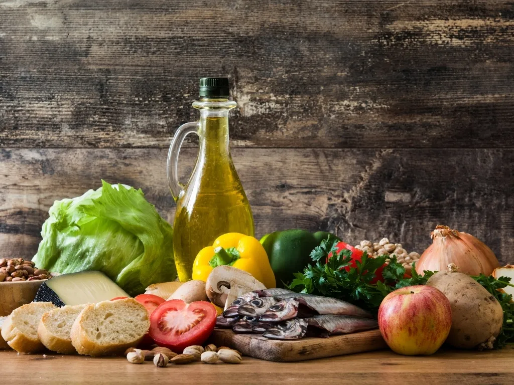 Mediterranean diet food composition presenting fresh fish, vegetables, fruits, olive oil, cheese, nuts and beans
