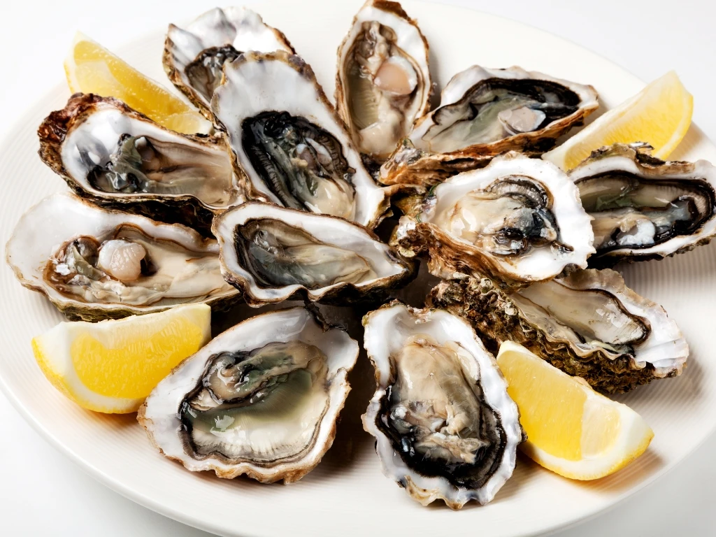 Plate of fresh oysters with lemon wedges