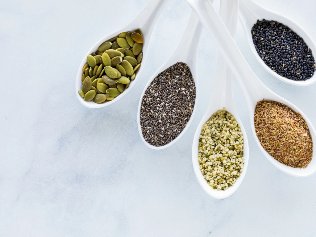 Five spoons, each filled with different kinds of seeds