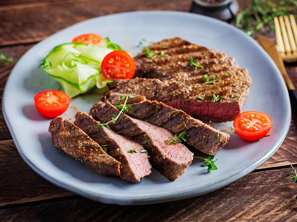 Sliced steak served with vegetables on a blue plate