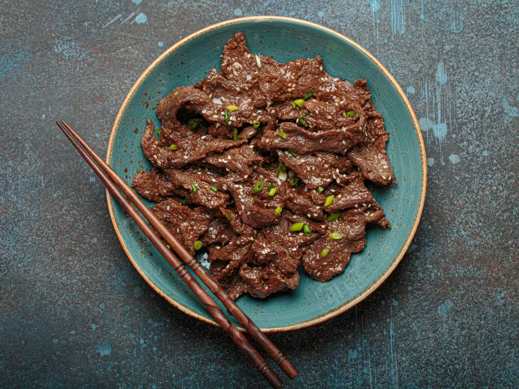 Beef bulgogi served on a blue plate with chopsticks