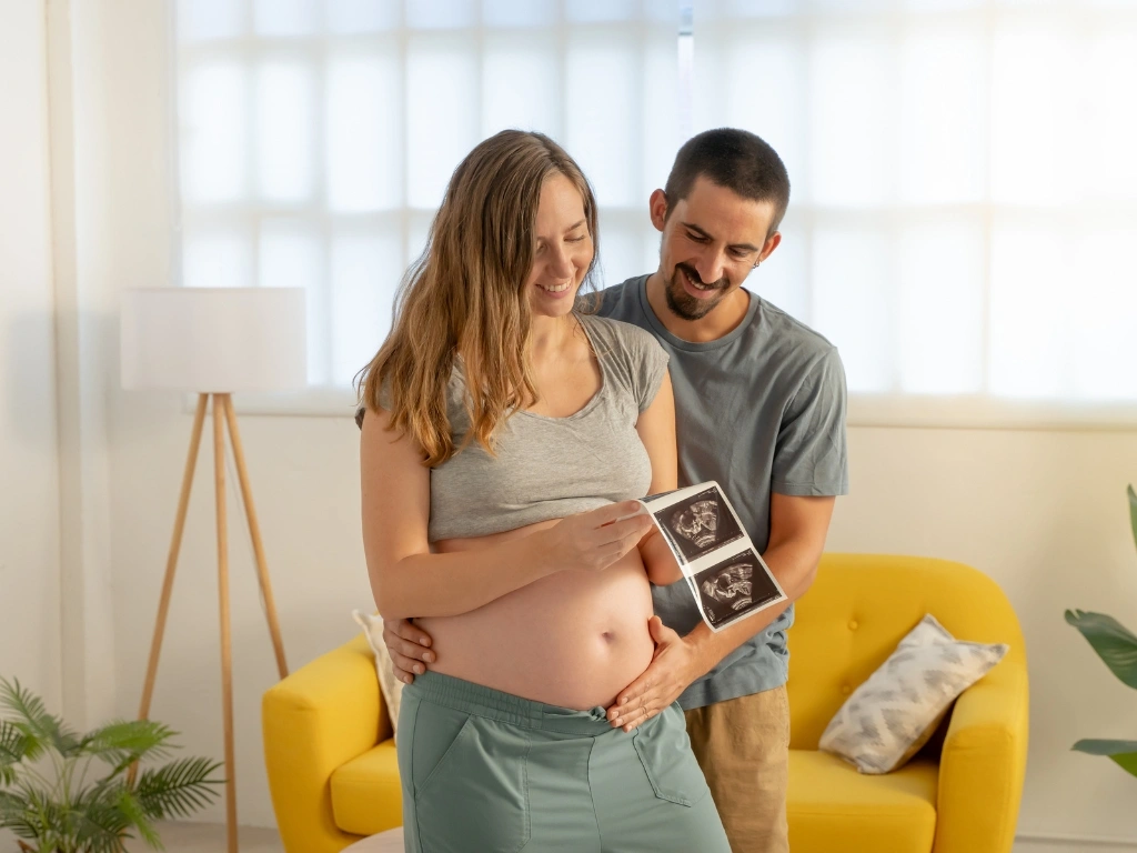Pregnant woman and husband looking at ultrasound images of their baby